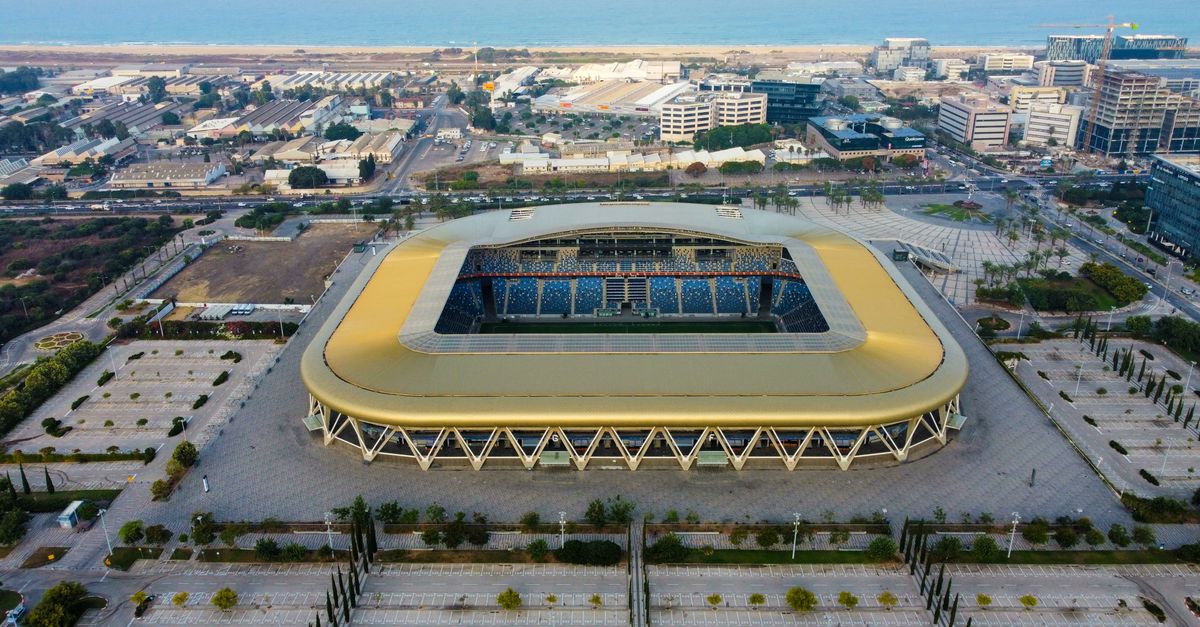 Aerial shot of a modern stadium near the coast with parking area.