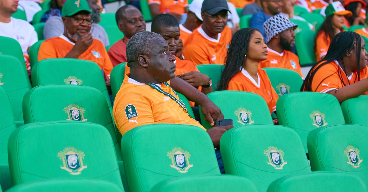 Excited spectators in orange jerseys filling stadium seats creating a vibrant scene.