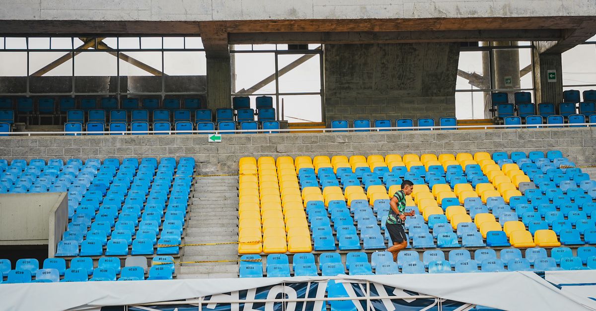 Colorful stadium seats with a single jogger running through them, showcasing athletics.